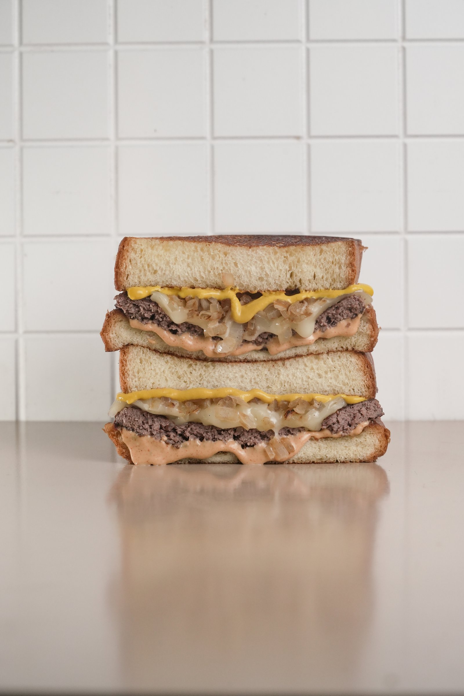 Cheesy Patty — brioche, beef patty, sauté onion, propola picante, secret sauce, yellow mustard